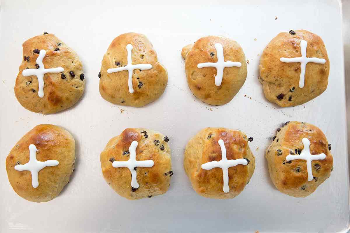 Two rows of Easter hot crossed buns cooling on a sheet pan