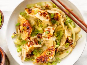 Gyoza with cabbage and green onions served in a bowl with chopsticks