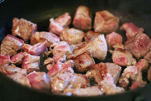 Pork cubes browning and cooking in a skillet