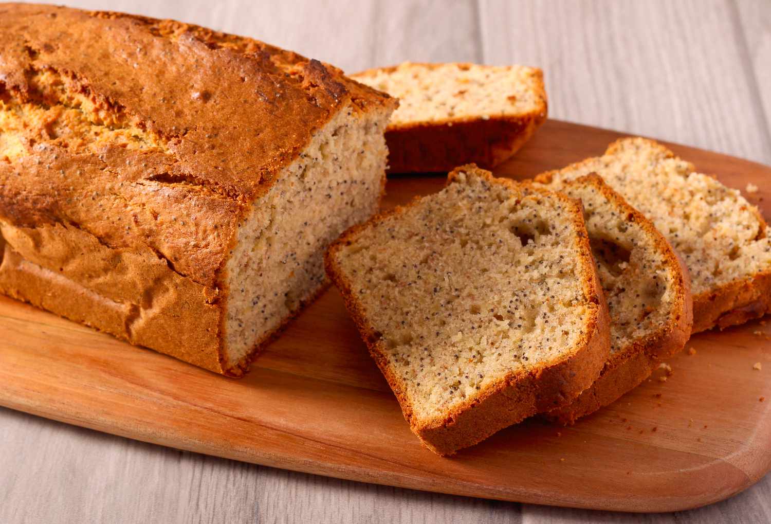 A partially-sliced loaf of banana bread on a cutting board