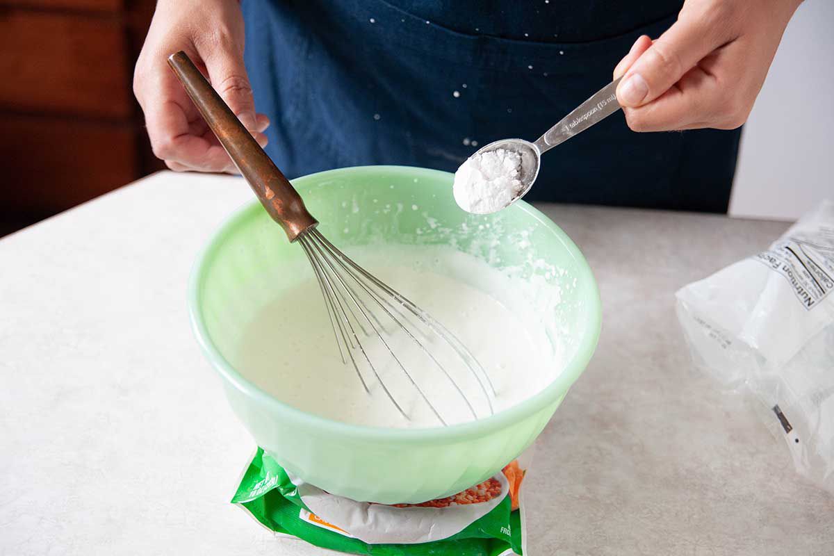 Sugar added to a bowl for a whipped cream recipe.