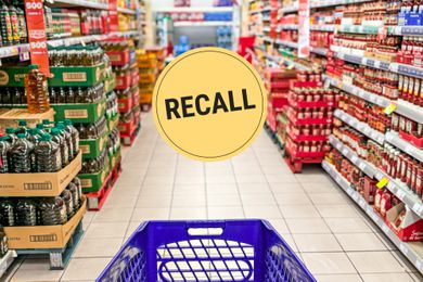 Looking down a grocery store aisle from behind a shopping cart. A "Recall" badge is superimposed over the center of the image.
