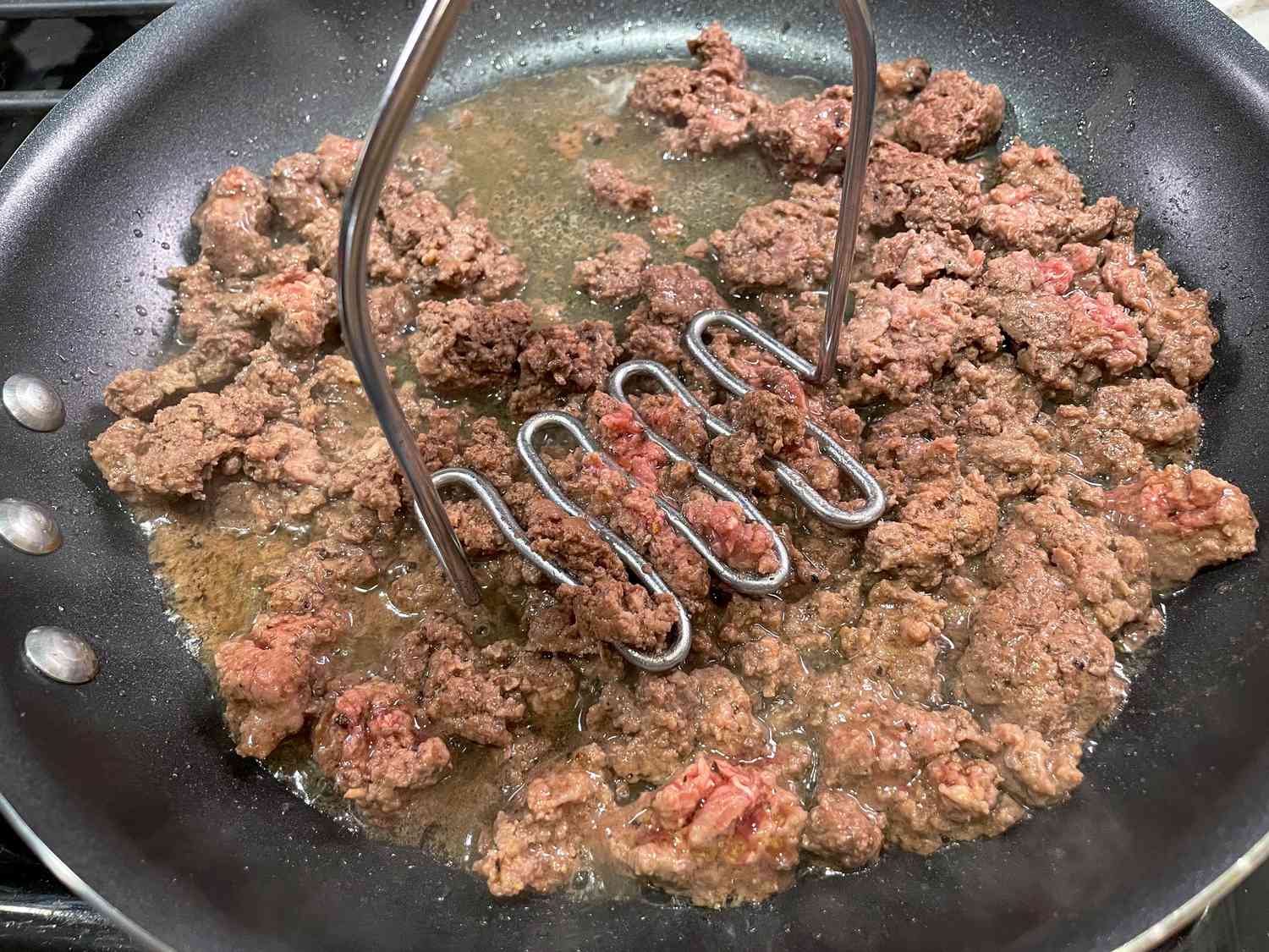 Breaking up ground beef with a potato masher