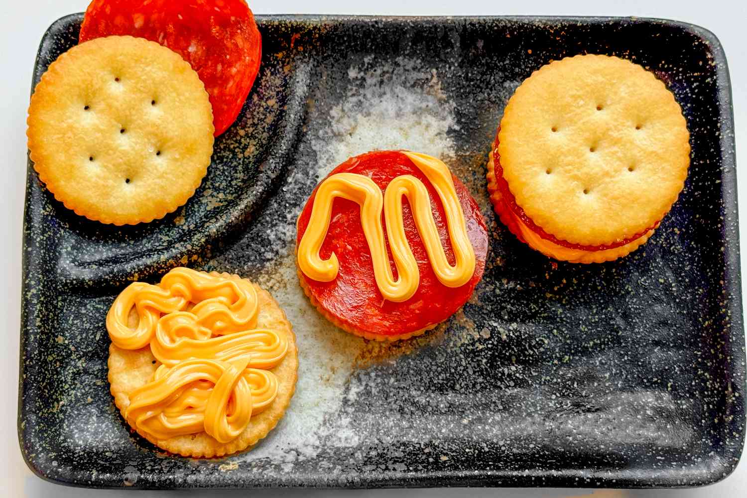 A plate with Ritz cracker pepperoni "pizzas" in the process of being assembled