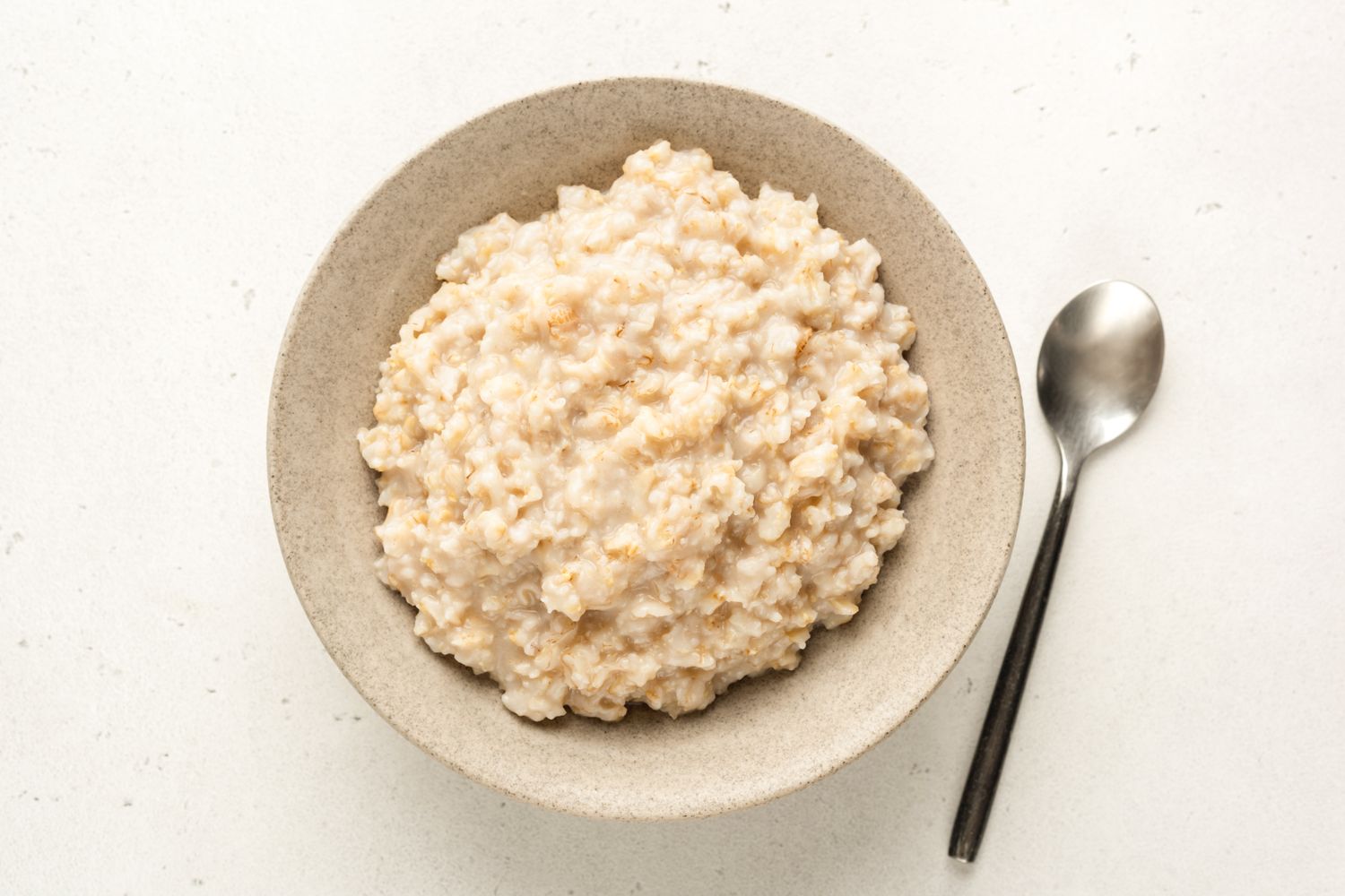 A bowl containing oatmeal accompanied by a spoon