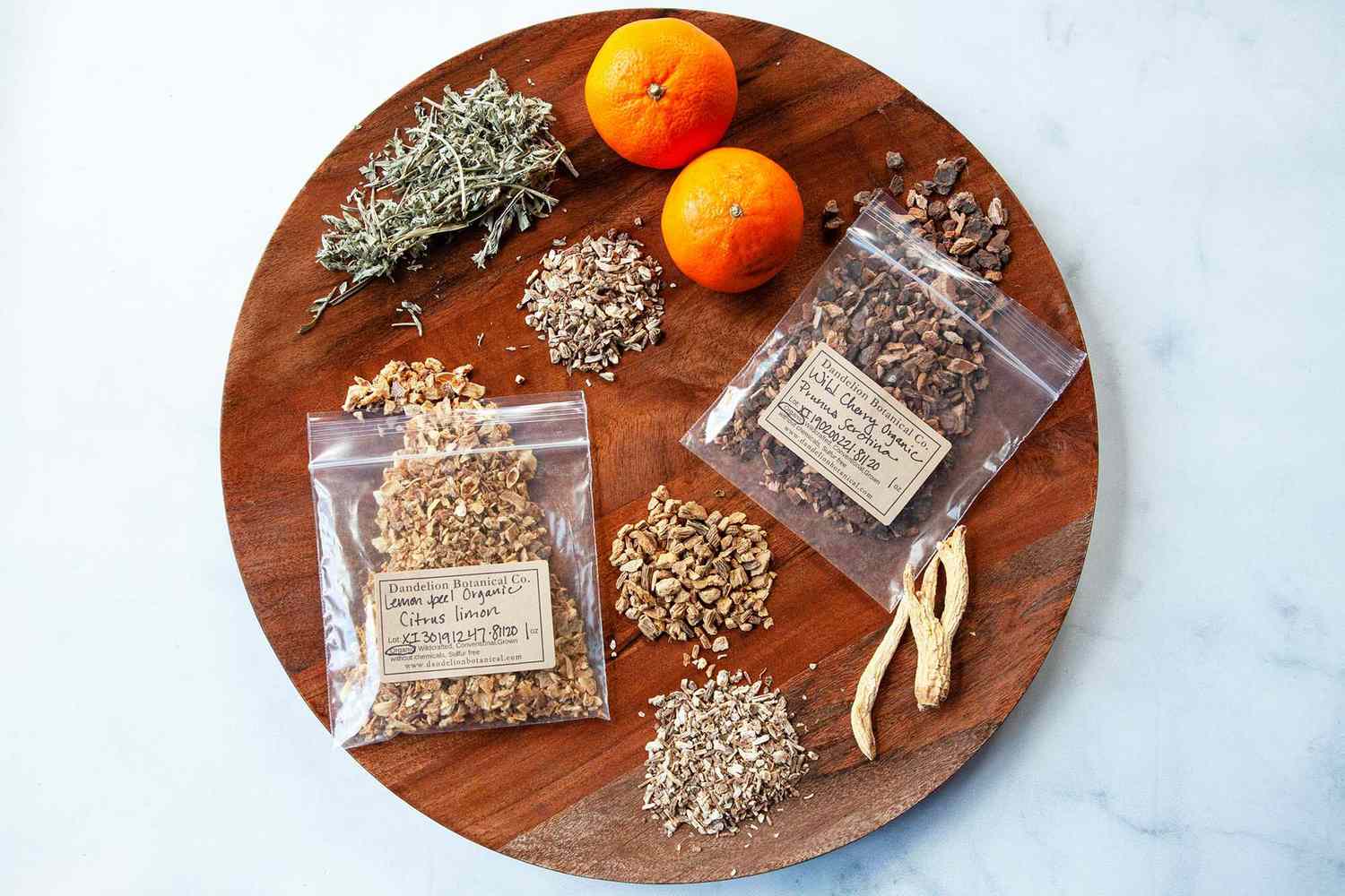 A round tray with spices, herbs and oranges set around it to make Campari.