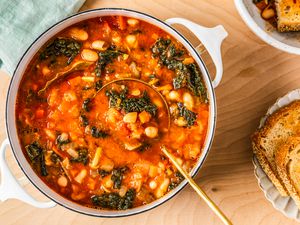 easy Tuscan ribolitta soup in a dutch oven at a table setting with a plate of bread and a kitchen towel