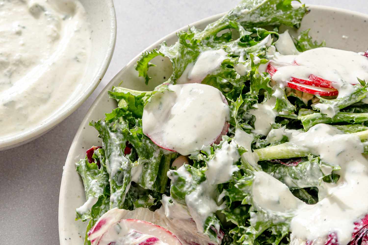 A plate of salad with sour cream and onion dressing poured over the greens and vegetables