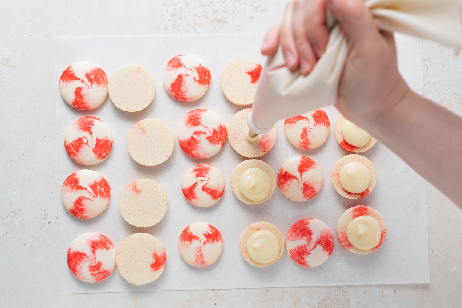 Adding ganache to the bottom shell to make peppermint macarons with white chocolate filling.