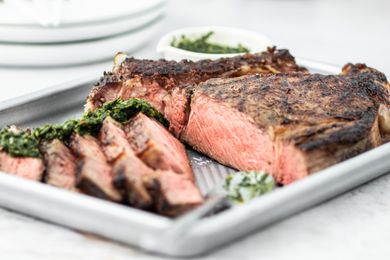 A cowboy ribeye steak sliced on a baking sheet