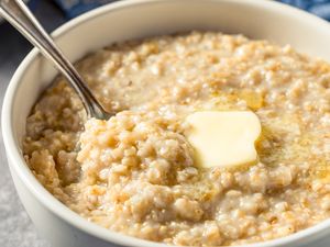A bowl of oatmeal with a dollop of butter and a spoon