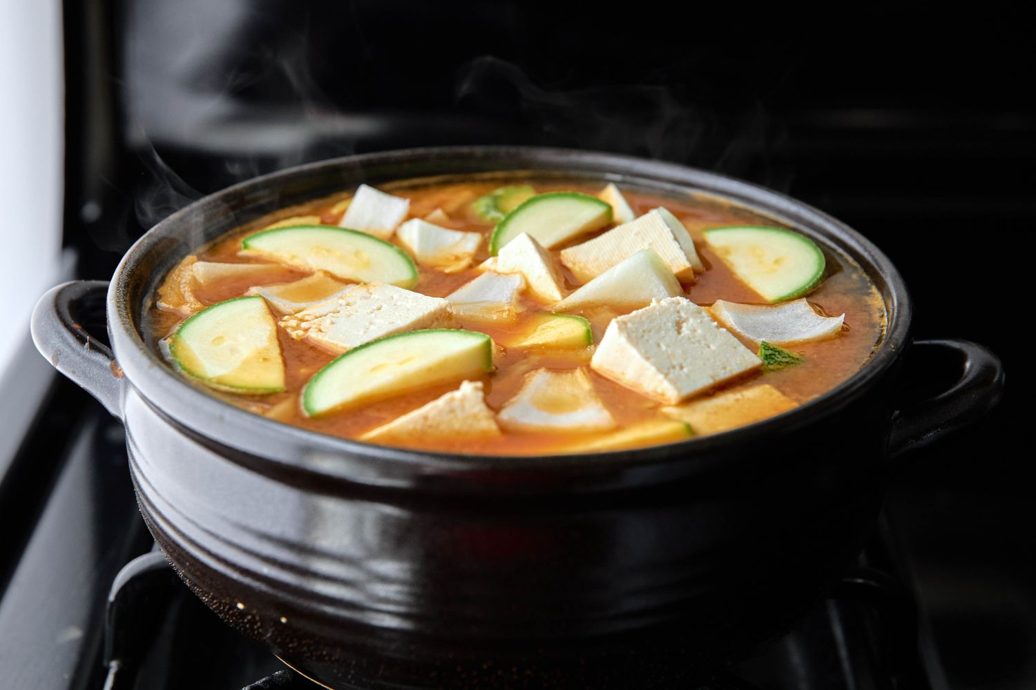 Clay Pot Filled With Deonjang Jjigae Ingredients Boiling on the Stove 