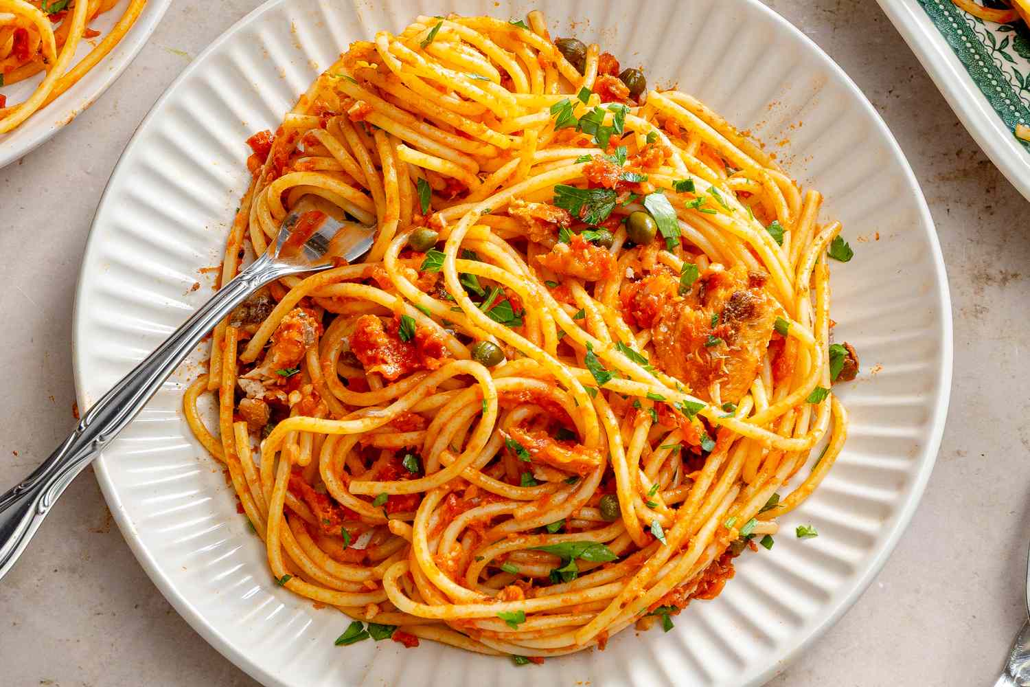 Plate of spaghetti with sardines garnished with herbs and olives