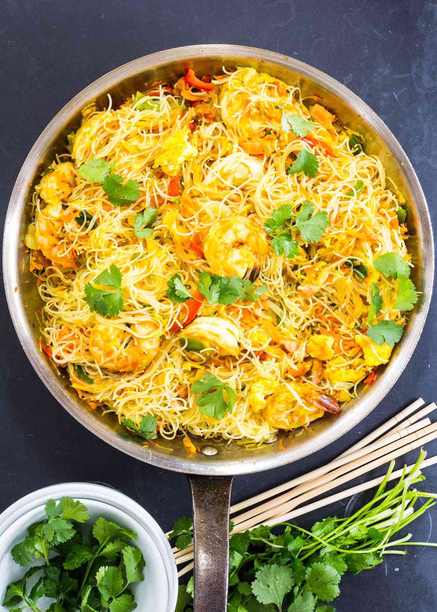 Singapore Style Noodles with Shrimp and cilantro in a skillet with chopsticks nearby
