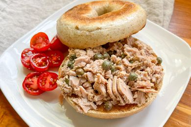 3-ingredient tuna salad on a toasted bagel on a plate with a serving of halved grape tomatoes