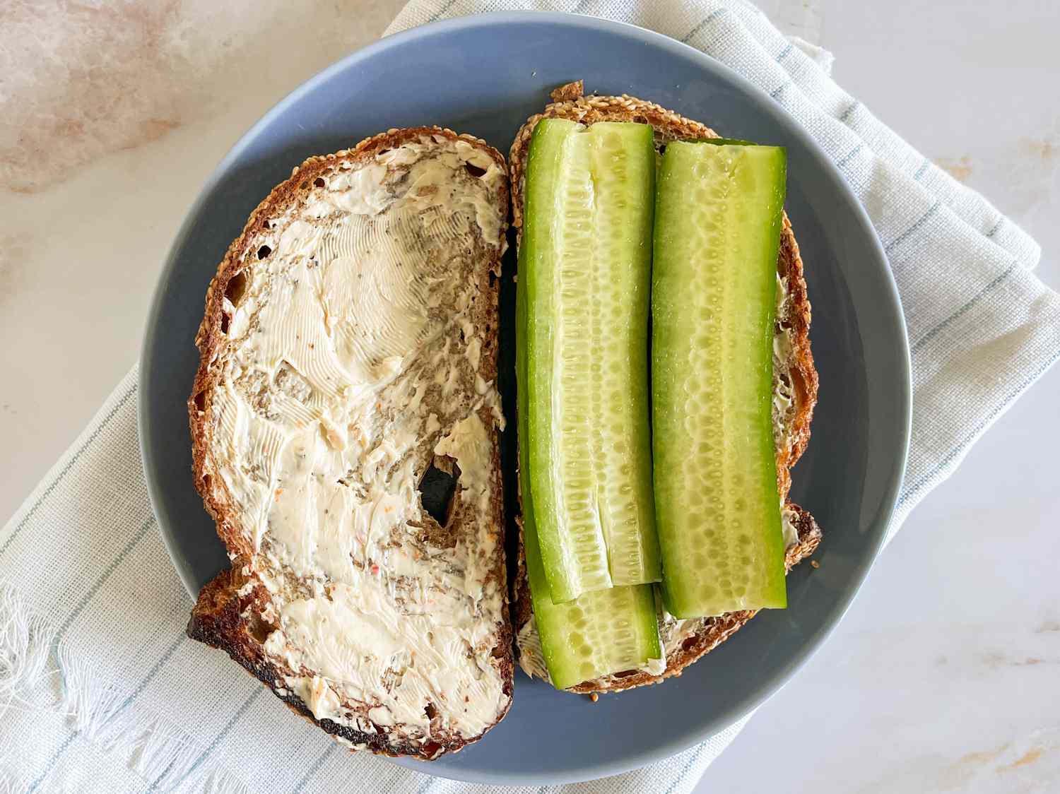 Sliced cucumber added to slices of bread with cream cheese 