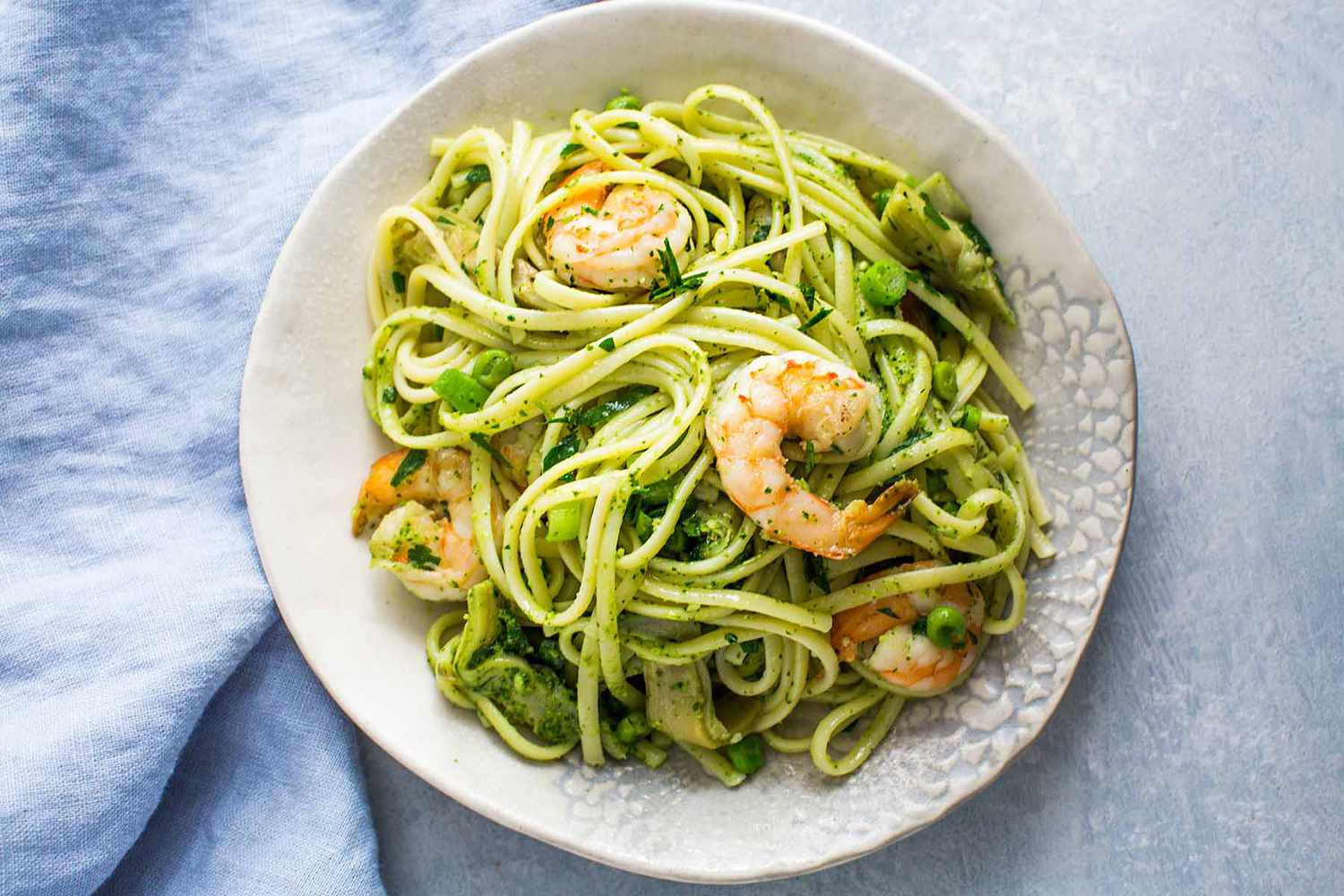 A serving bowl of shrimp and artichoke pasta