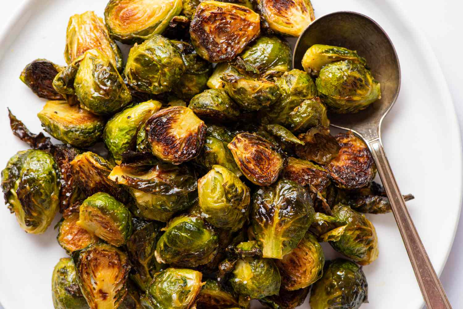 A closeup of roasted Brussels sprouts on a white serving plate