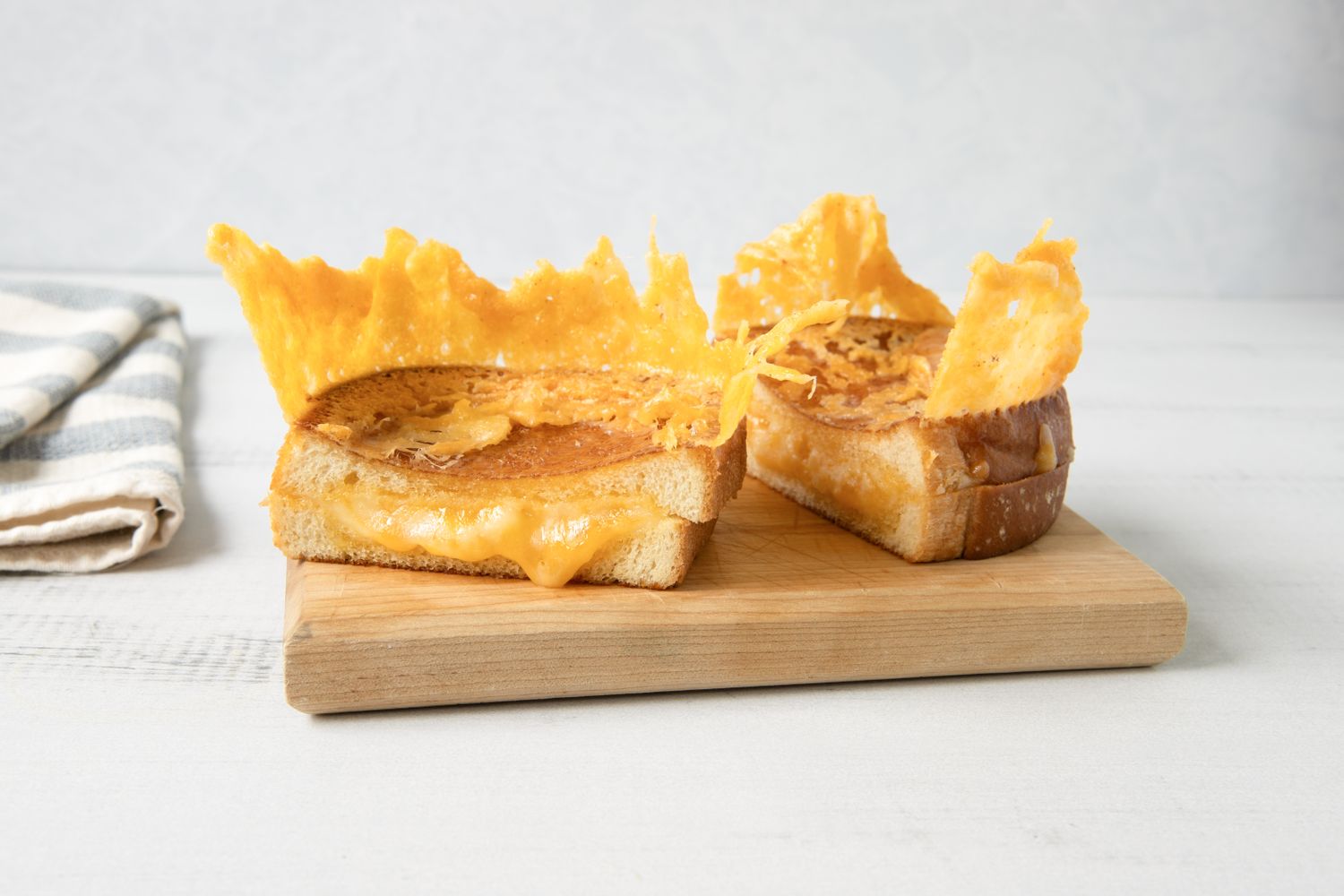 Grilled cheese sandwiches with crispy cheese topping on a wooden board
