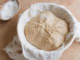 Dough in a towel lined bowl to make spiced sourdough bread shaped like a pumpkin