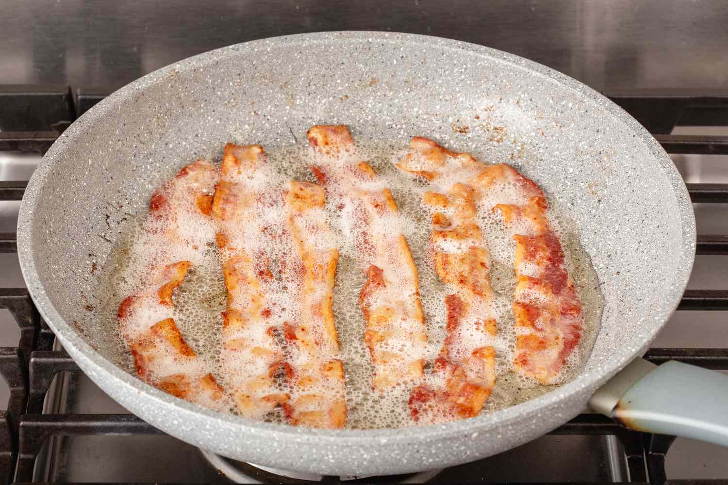 Frying bacon in a skillet to make the best potato salad recipe.