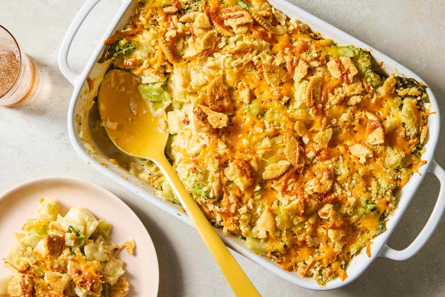 Casserole dish with cabbage casserole and a serving spoon next to a plate with a portion of the dish