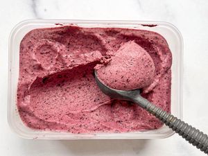 Frozen yogurt being scooped from a container with a metal ice cream scoop