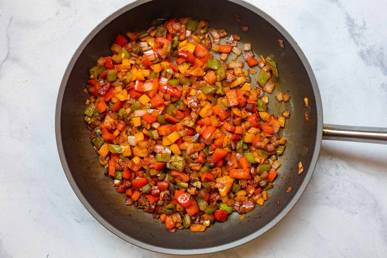 A skillet with chopped vegetables to make black bean, corn, and pepper freezer burritos.