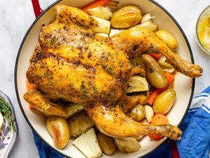 Cooked roast chicken in a dish with potatoes and vegetables