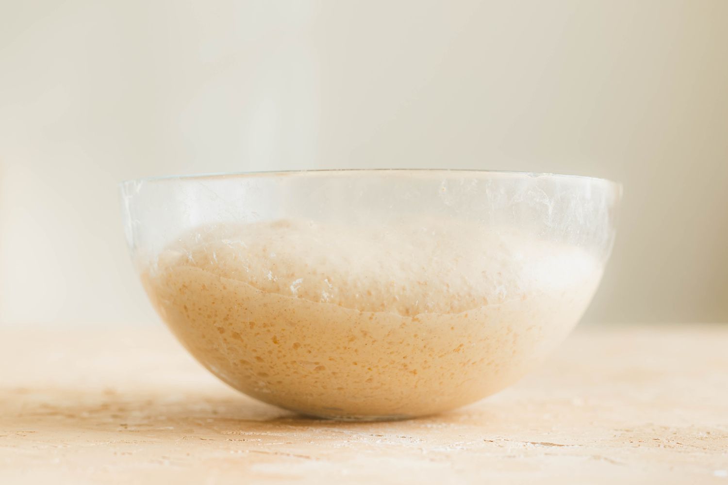Dough for spiced sourdough bread shaped like a pumpkin rising in a glass bowl.