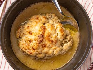 Cooked cauliflower in a pot with a spoon over liquid