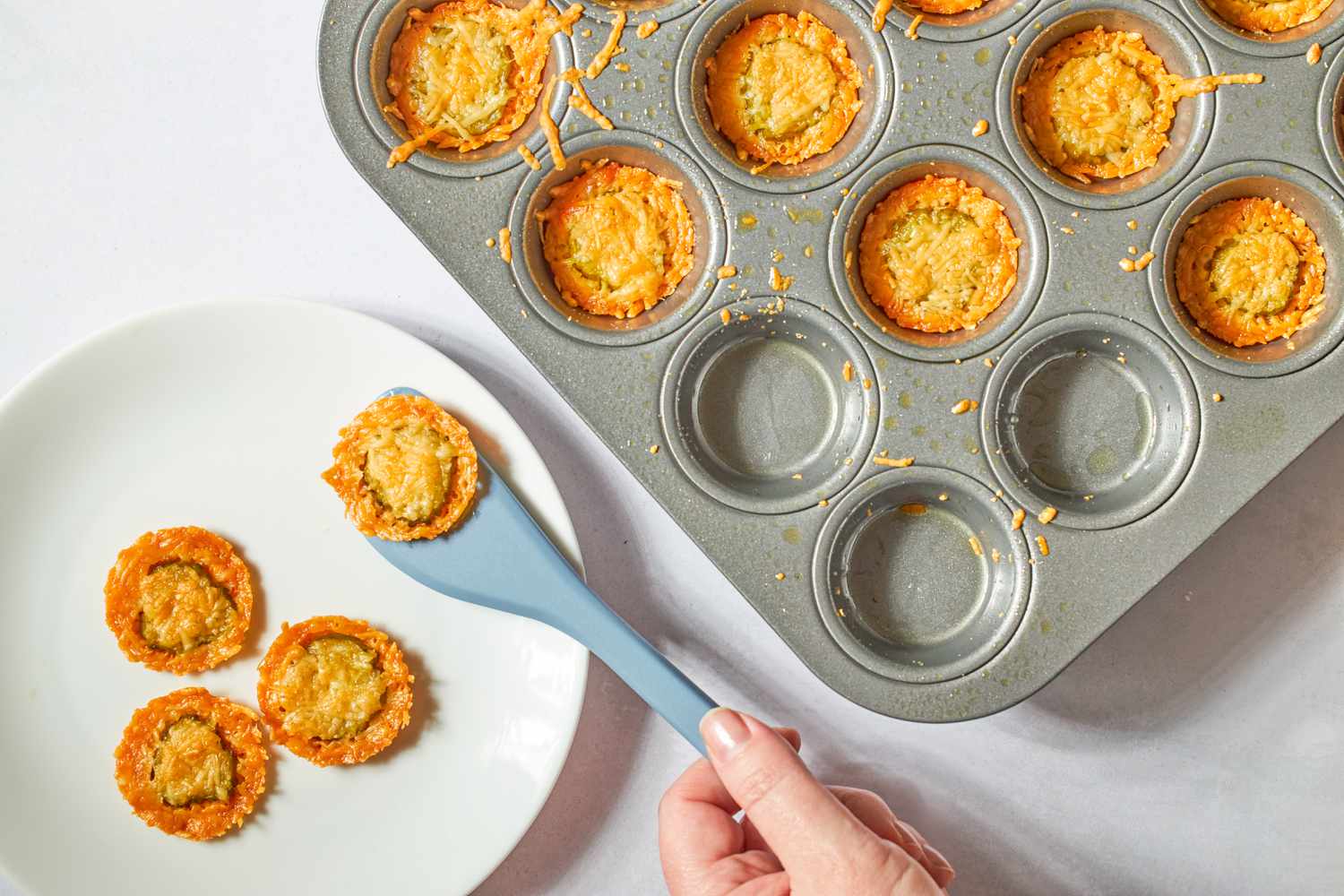 Baked fried pickles in a muffin tin and on a plate with a spatula