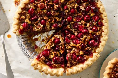 Cranberry pecan pie with a slice removed displayed in a pie dish