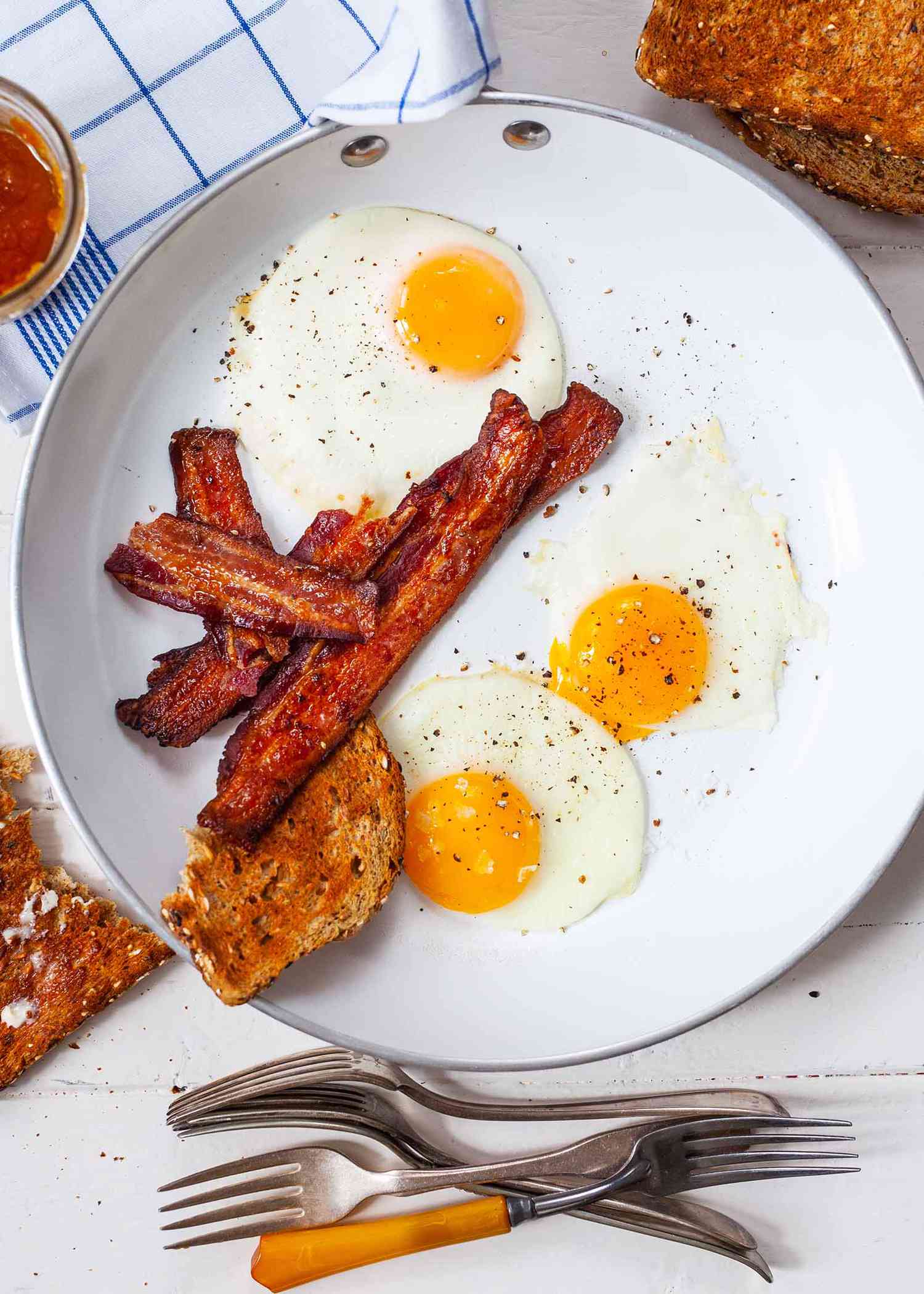 Over easy eggs on a plate with a side of bacon.