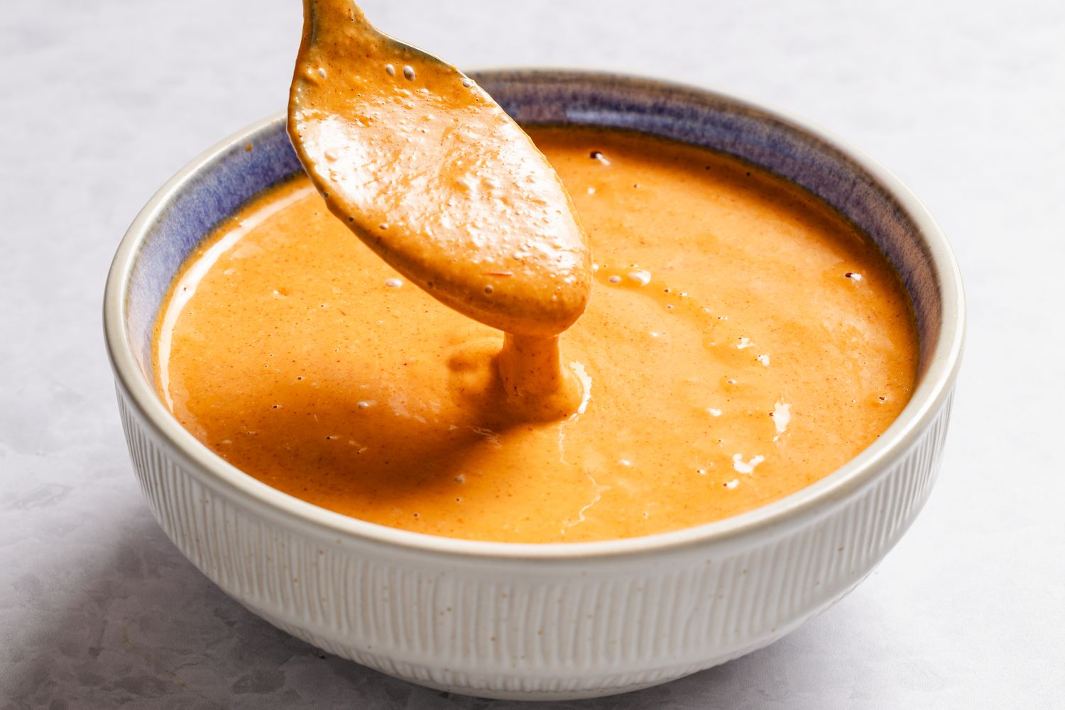 A bowl of Mississippi comeback sauce with a spoon dipping into it