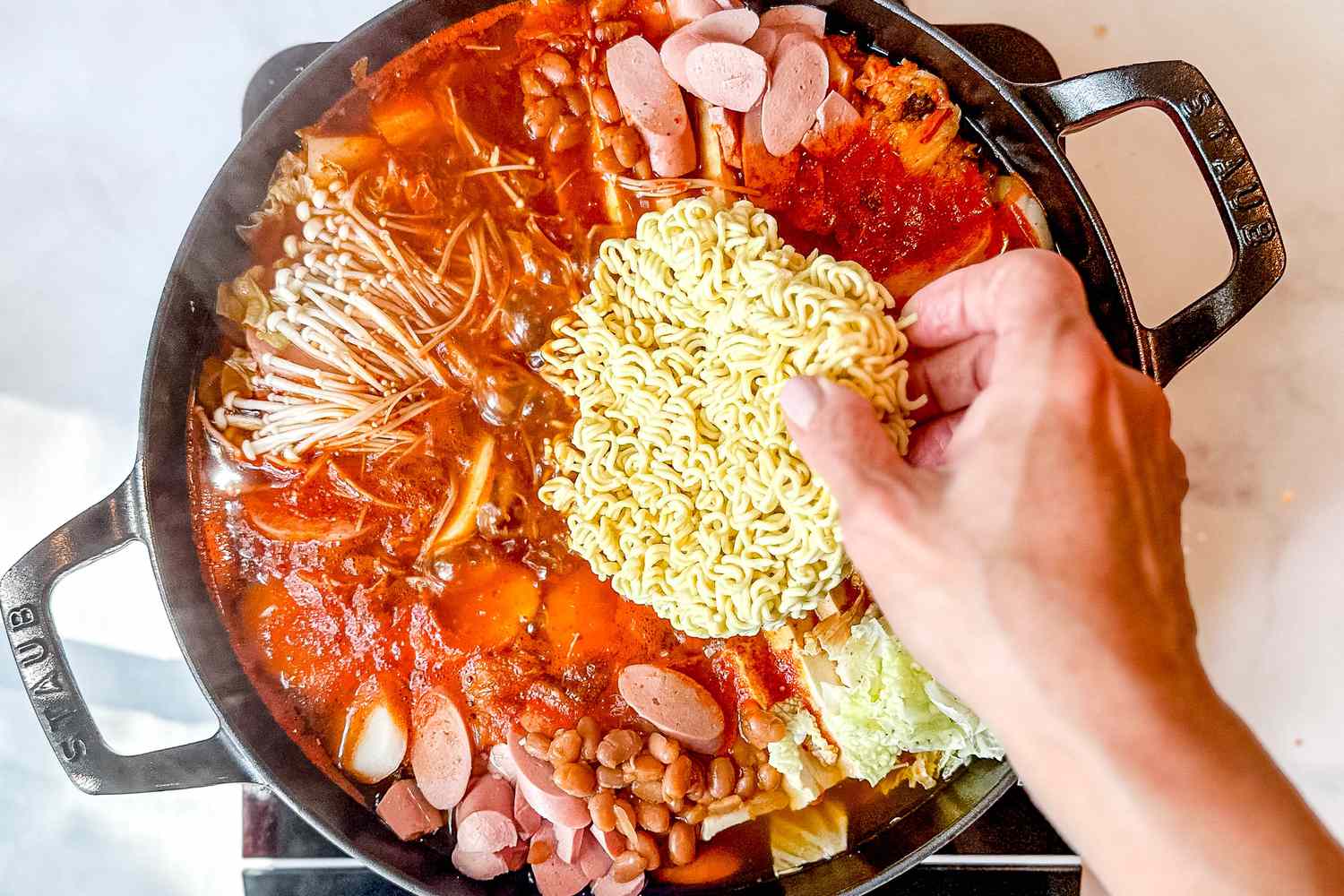 Ramen noodles added to the center of the pot as the budae jjigae ingredients boil