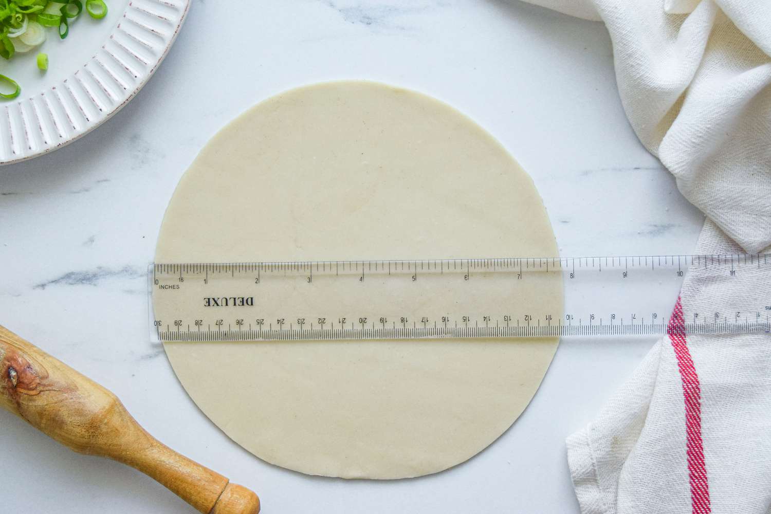Ruler set of a round of dough to make scallion pancakes.