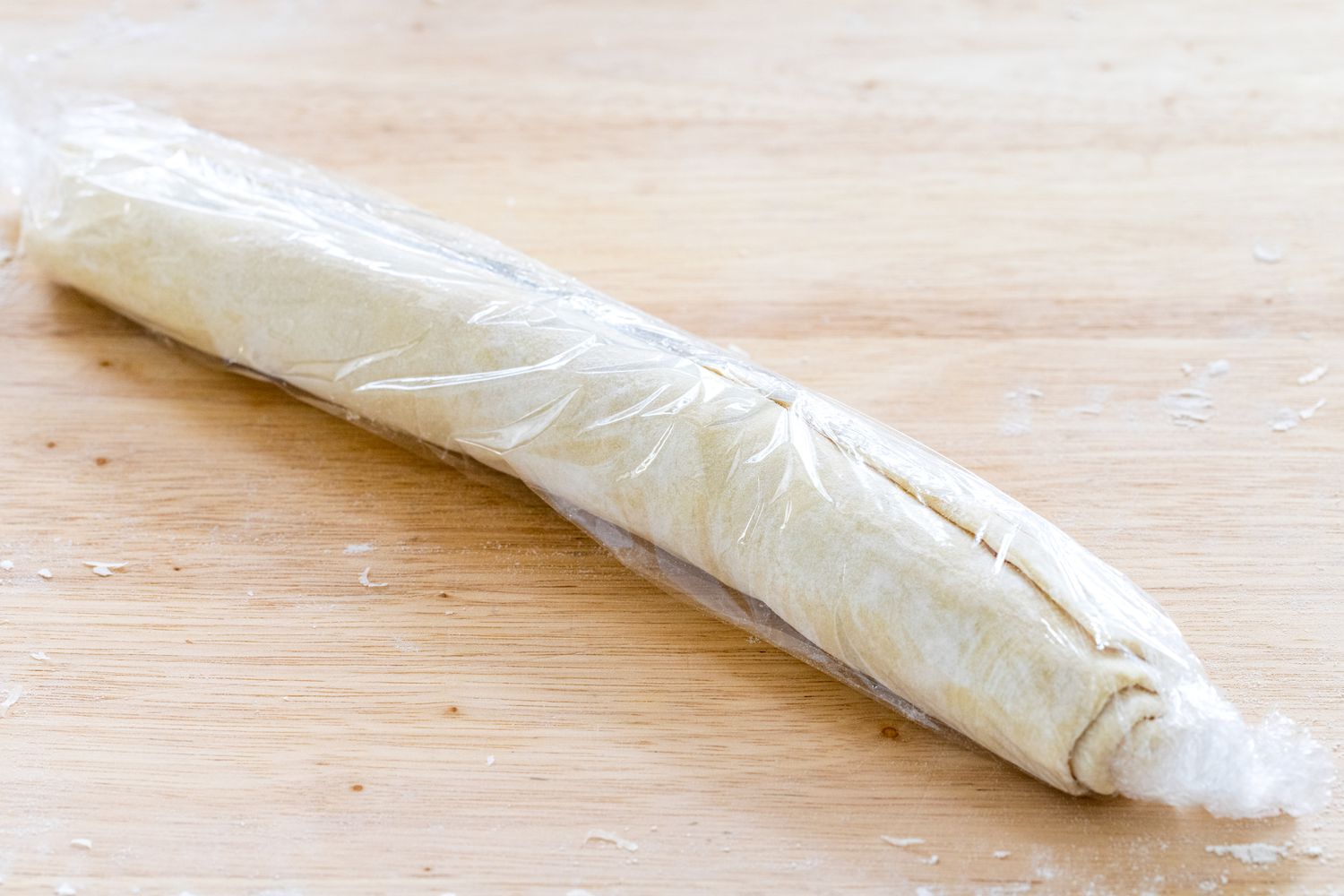 The filled puff pastry wrapped in plastic wrap to make crispy prosciutto and parmesan pinwheels.