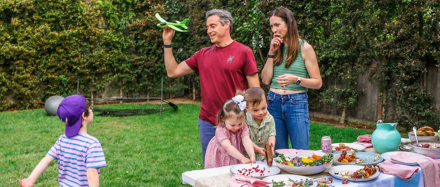 The Pfeffer parents and their three children play outside alongside a table of food