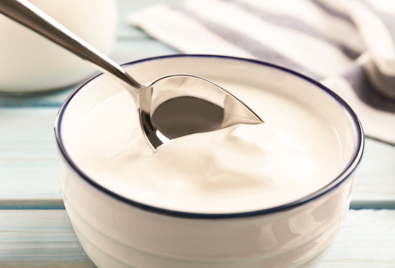 A bowl of yogurt with a metal spoon resting on it