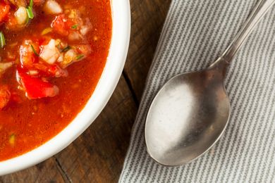 A bowl of soup next to a spoon on a striped napkin