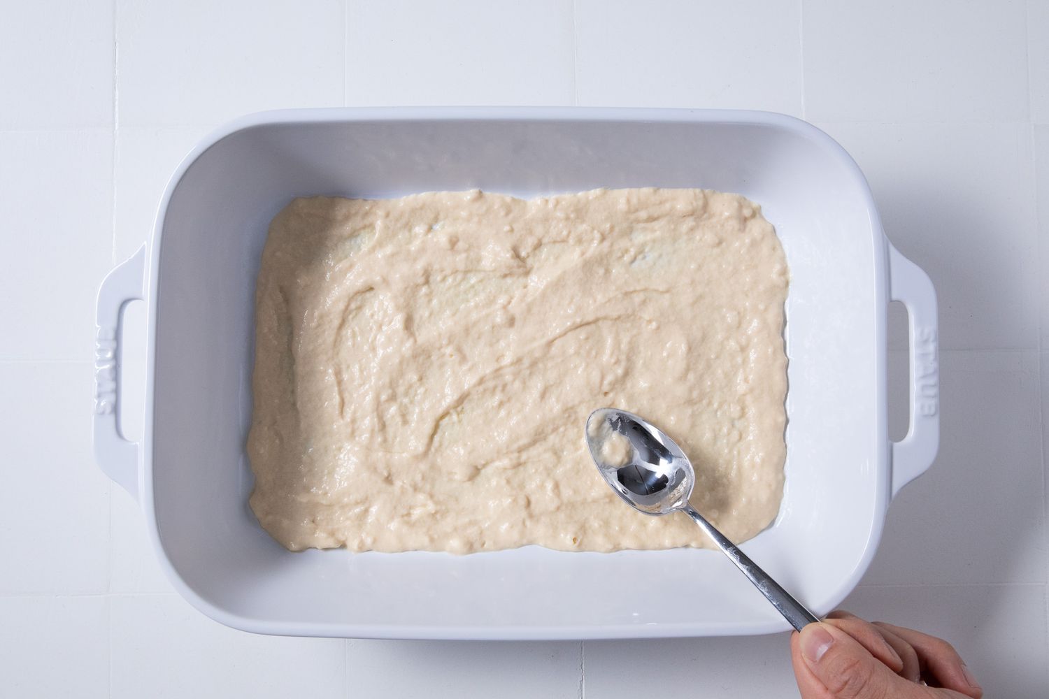 thin layer of wet batter added to casserole dish for batsaria recipe