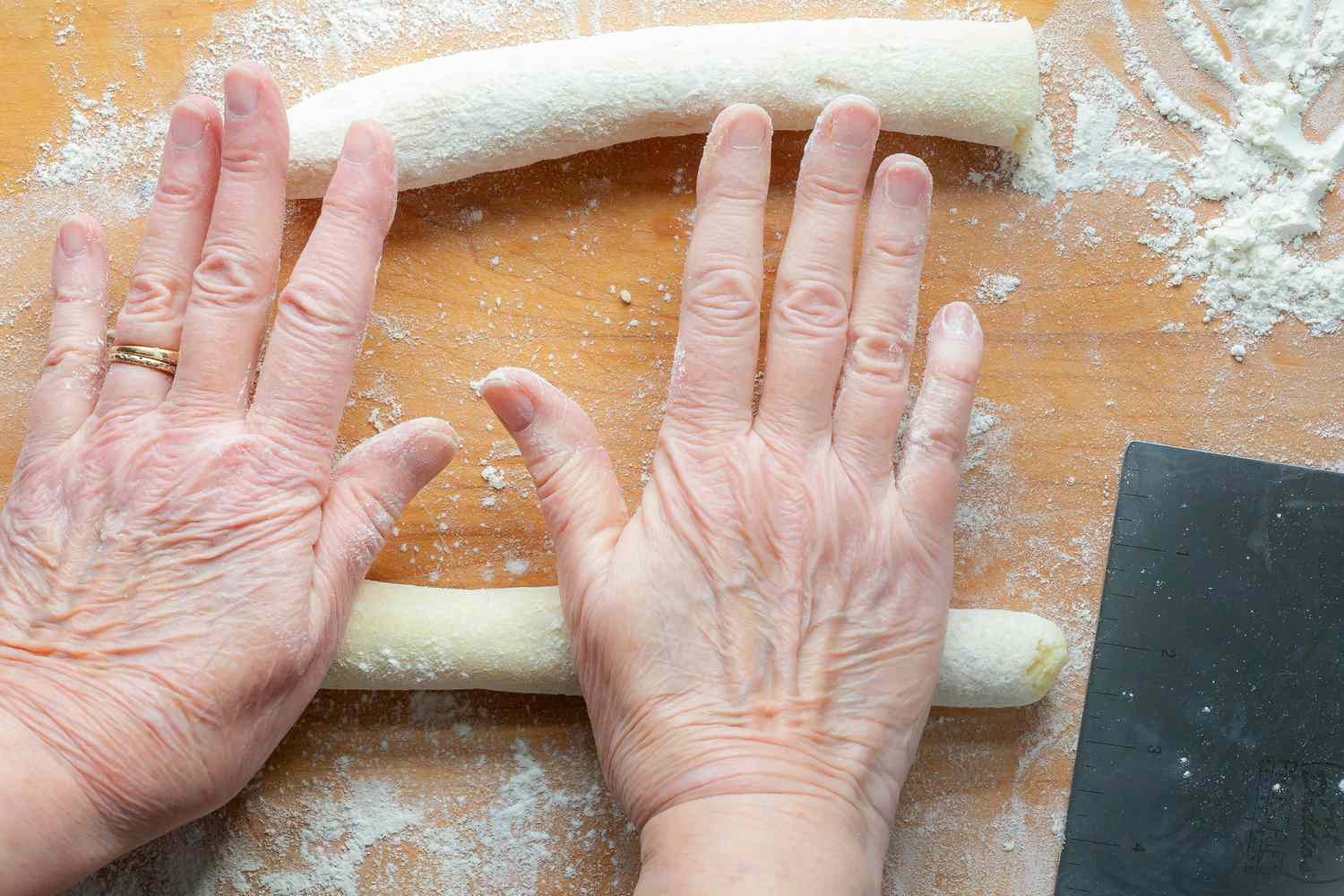 Hands showing how to shape logs of dough to make potato gnocchi