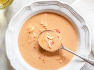 Bowl of Lobster Bisque with a Spoon Next to a Glass