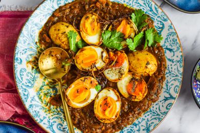 Plate of Egg Masala Curry with a Spoon on a Kitchen Linen
