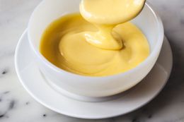 Side view of Classic Hollandaise Sauce in a small bowl with a spoon.