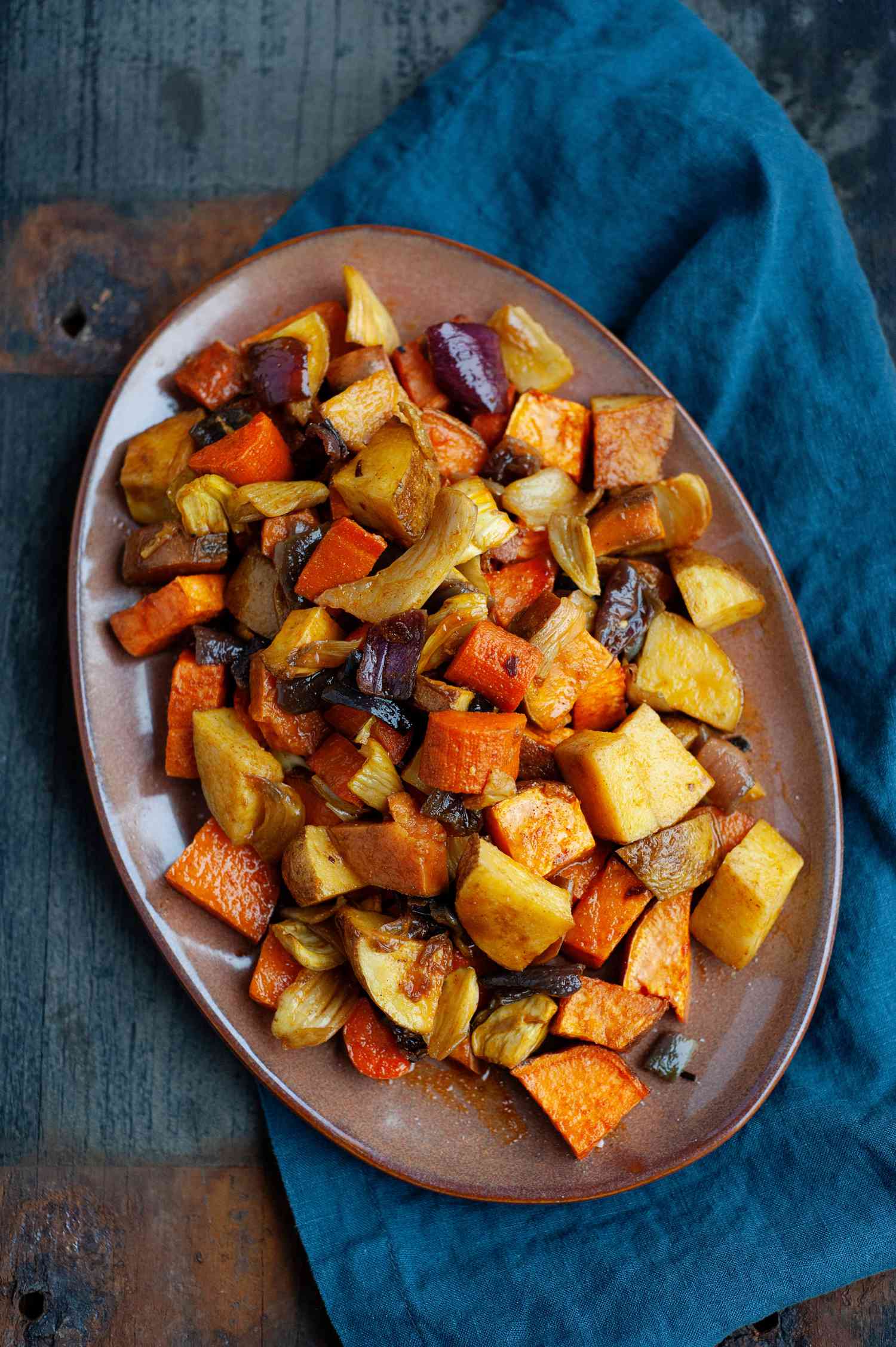 Overhead view of a easy roasted vegetables on a platter with a teal linen underneath.