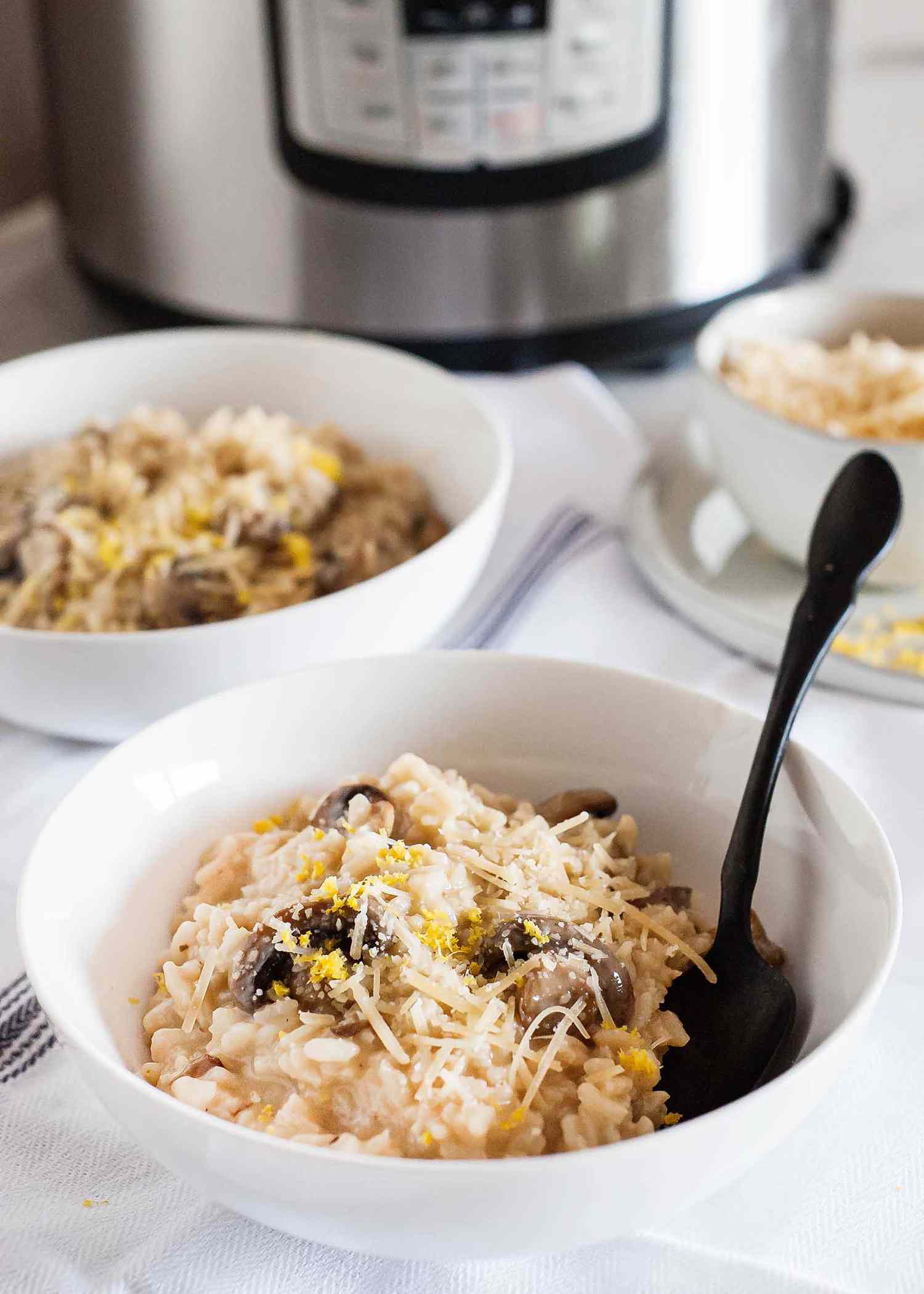 Insta Pot Mushroom Risotto -- white bowls filed creamy mushroom risotto in front of an Instant Pot