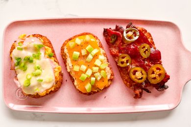 Three hashbrown patties topped with a variety of ingredients presented on a pink platter
