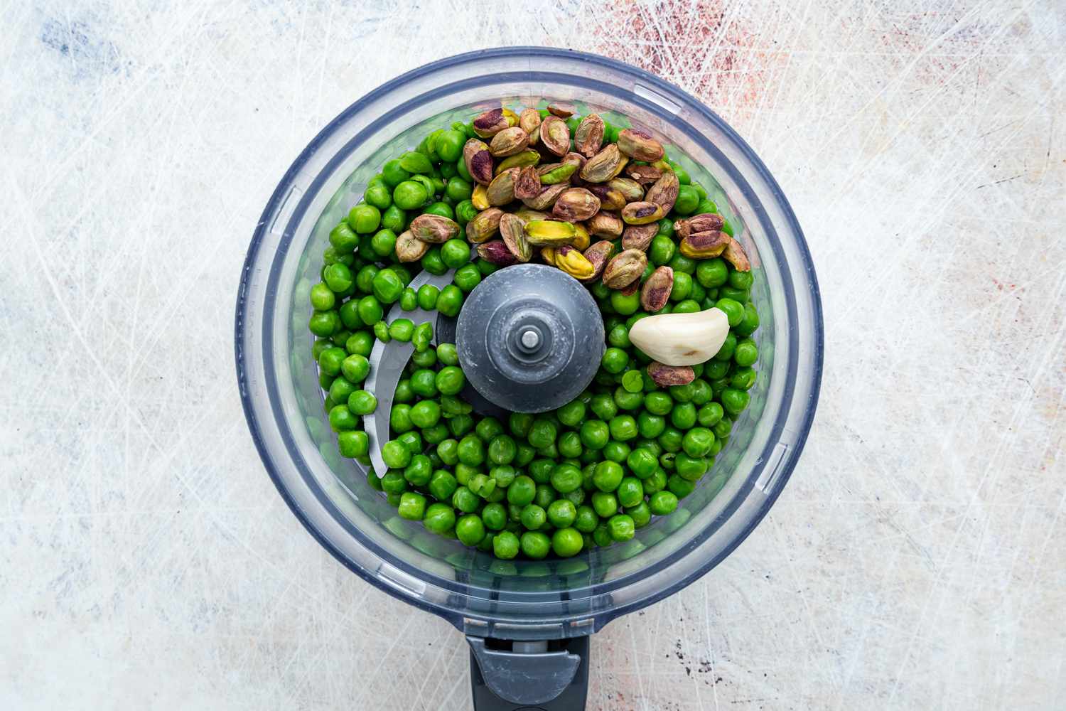 Pea Pesto Ingredients (Thawed Peas, Pistachios, and a Clove of Garlic) in a Food Processor